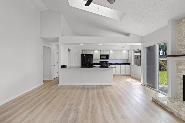 kitchen featuring black appliances, dark countertops, a ceiling fan, a fireplace, and a textured ceiling