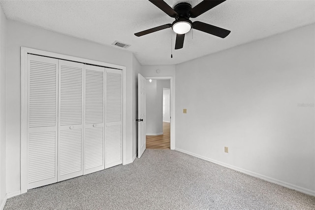 unfurnished bedroom featuring carpet, a closet, baseboards, a textured ceiling, and a ceiling fan