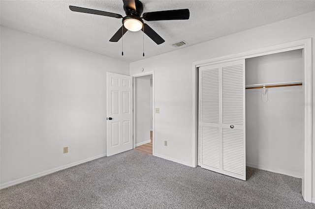 unfurnished bedroom with a textured ceiling, carpet floors, a closet, a ceiling fan, and baseboards