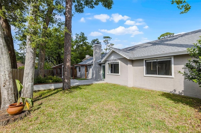 back of property featuring stucco siding, a shingled roof, and a chimney