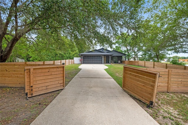 view of yard with concrete driveway and fence