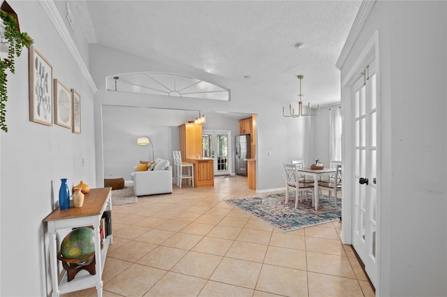 dining space featuring a chandelier, light tile patterned flooring, baseboards, a textured ceiling, and lofted ceiling