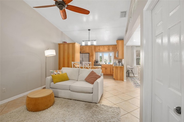 living area with light tile patterned floors, a ceiling fan, and baseboards
