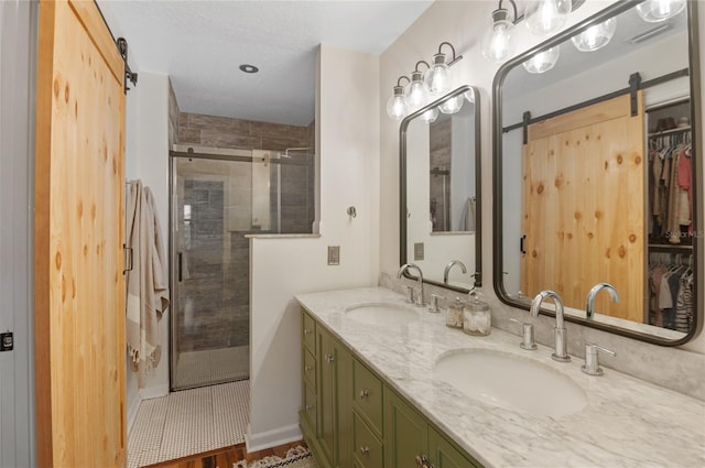 bathroom featuring a stall shower, double vanity, and a walk in closet