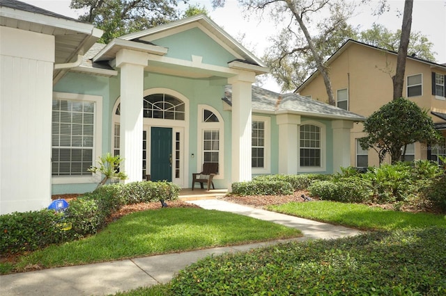 4201 Old Trafford Way, Orlando, FL 32810 - doorway to property featuring stucco siding, a lawn, and a porch