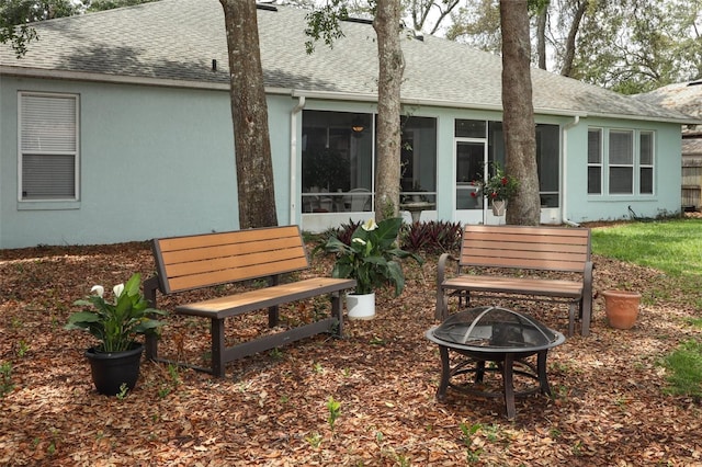 4201 Old Trafford Way, Orlando, FL 32810 - back of property with a fire pit, roof with shingles, a sunroom, and stucco siding