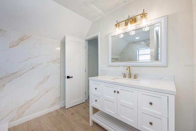 712 Maryland Ave, Saint Cloud, FL 34769 - bathroom featuring a marble finish shower, vanity, wood finished floors, baseboards, and vaulted ceiling