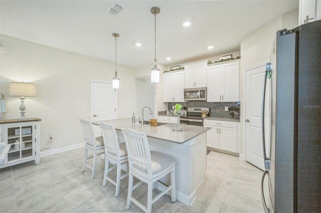 8907 Fallen Oak, Davenport, FL 33897 - kitchen with stainless steel appliances, white cabinets, decorative backsplash, a kitchen breakfast bar, and an island with sink