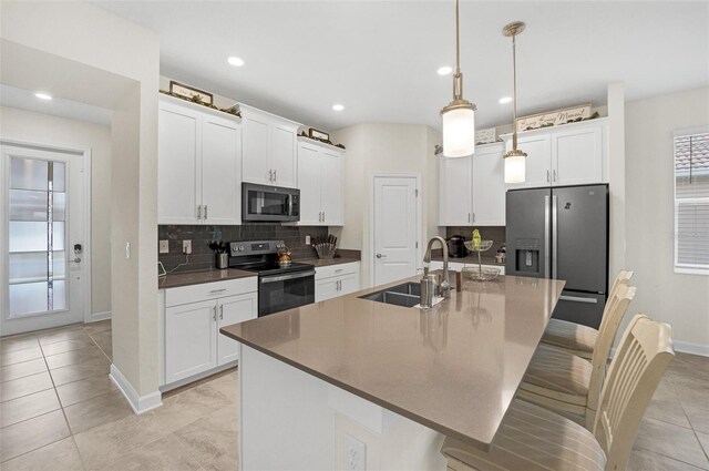 8907 Fallen Oak, Davenport, FL 33897 - kitchen featuring appliances with stainless steel finishes, a sink, a breakfast bar, baseboards, and backsplash