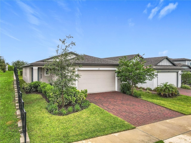 view of front of property with decorative driveway, a garage, stucco siding, a front yard, and a shingled roof