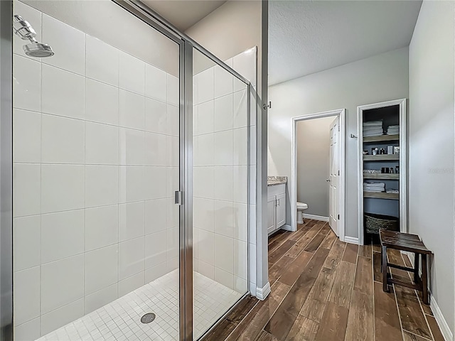 full bathroom featuring wood finished floors, a stall shower, and toilet