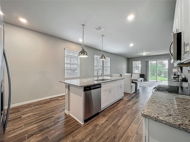 kitchen featuring appliances with stainless steel finishes, a sink, dark wood-style flooring, a kitchen island with sink, and white cabinetry