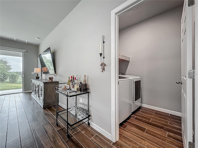 clothes washing area featuring separate washer and dryer, wood finish floors, and baseboards