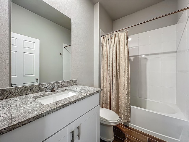 bathroom featuring wood finished floors, toilet, shower / bath combination with curtain, vanity, and a textured wall