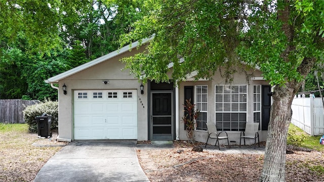 view of front of property featuring fence, stucco siding, an attached garage, and concrete driveway