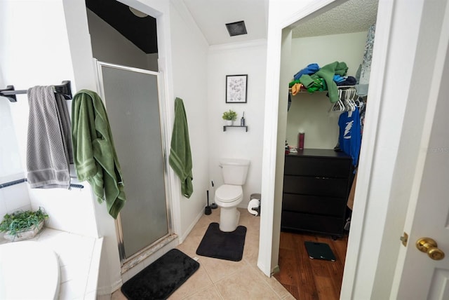 full bath with a stall shower, a spacious closet, toilet, and tile patterned floors