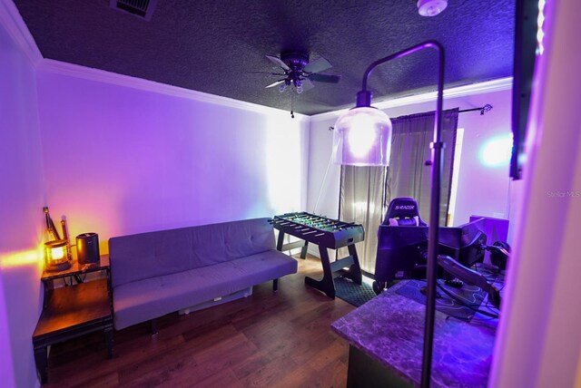 interior space with ornamental molding, ceiling fan, wood finished floors, and a textured ceiling