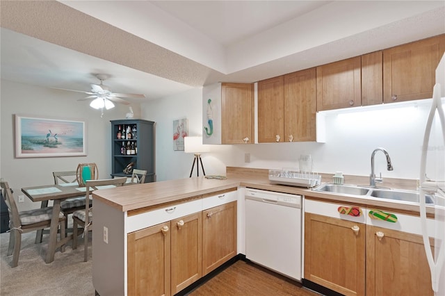 kitchen featuring dishwasher, a peninsula, a sink, and light countertops