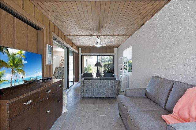 living room with a textured wall, wood ceiling, light wood-style flooring, and ceiling fan