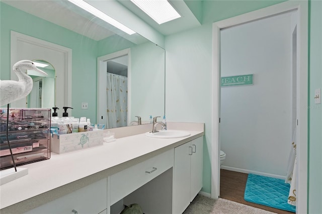 bathroom featuring toilet, vanity, and baseboards