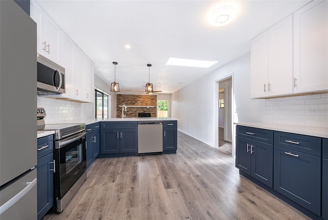 713 Coach Light Dr, Fern Park, FL 32730 - kitchen with stainless steel appliances, a skylight, a peninsula, blue cabinets, and decorative backsplash