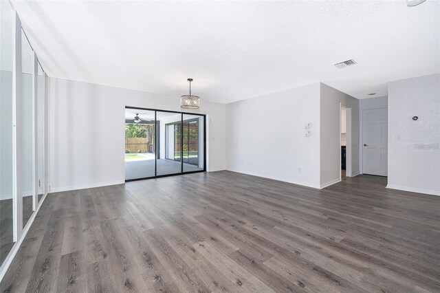 713 Coach Light Dr, Fern Park, FL 32730 - unfurnished living room featuring dark wood-type flooring, a chandelier, baseboards, and a textured ceiling