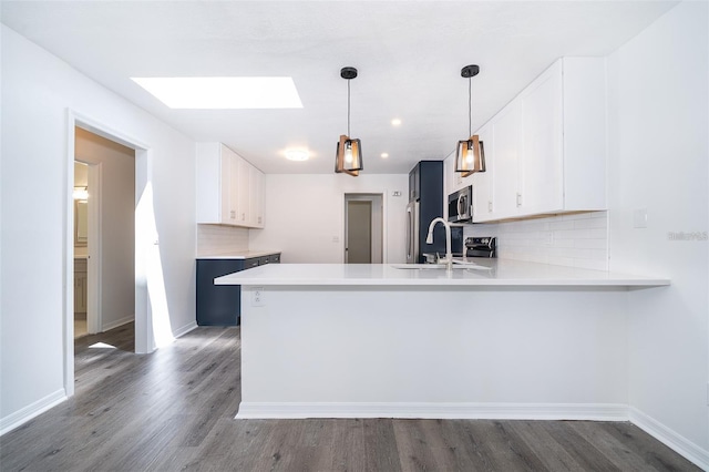 713 Coach Light Dr, Fern Park, FL 32730 - kitchen with stainless steel microwave, a sink, a skylight, a peninsula, and tasteful backsplash