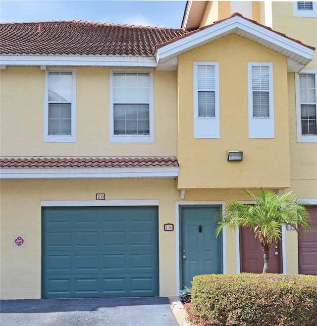 12212 Wild Iris Way Unit 106, Orlando, FL 32837 - townhome / multi-family property featuring a tiled roof, a garage, stucco siding, and asphalt driveway