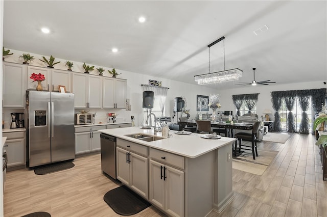 kitchen featuring stainless steel appliances, a sink, light countertops, light wood-type flooring, and recessed lighting