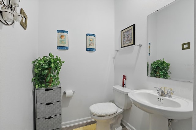 half bathroom with toilet, baseboards, a sink, and wood finished floors