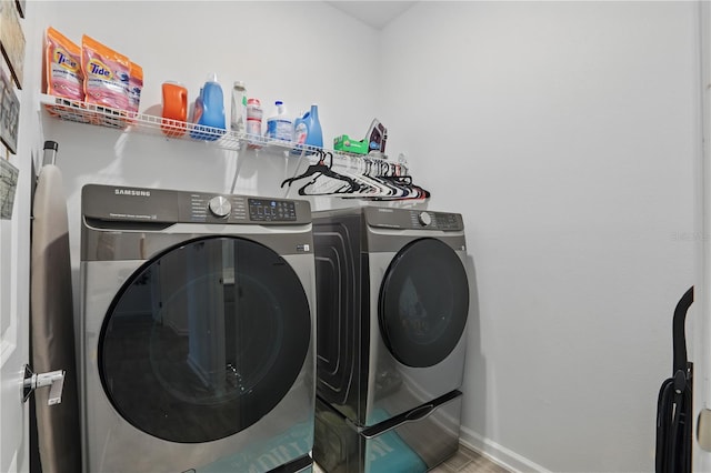 clothes washing area with washing machine and dryer and baseboards