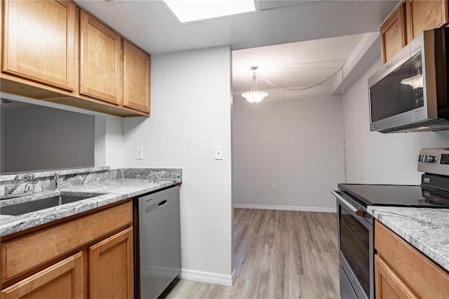 1163 Paseo Del Mar Unit B, Casselberry, FL 32707 - kitchen with stainless steel appliances, a sink, light wood-style flooring, light stone counters, and baseboards