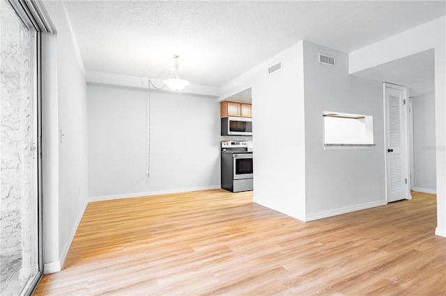 1163 Paseo Del Mar Unit B, Casselberry, FL 32707 - kitchen with stainless steel electric range oven, white microwave, light wood finished floors, baseboards, and a textured ceiling