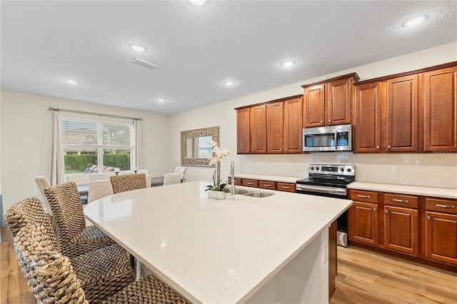 257 Auburn Ave, Kissimmee, FL 34747 - kitchen featuring stainless steel appliances, a sink, light wood finished floors, light countertops, and a breakfast bar area