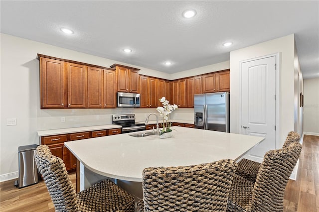 257 Auburn Ave, Kissimmee, FL 34747 - kitchen with stainless steel appliances, a sink, a breakfast bar, light wood-style flooring, and recessed lighting