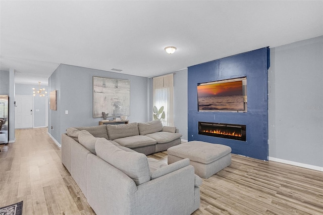 3519 Fernanda Dr, Deltona, FL 32738 - living room featuring light wood-style flooring, a chandelier, a large fireplace, and baseboards