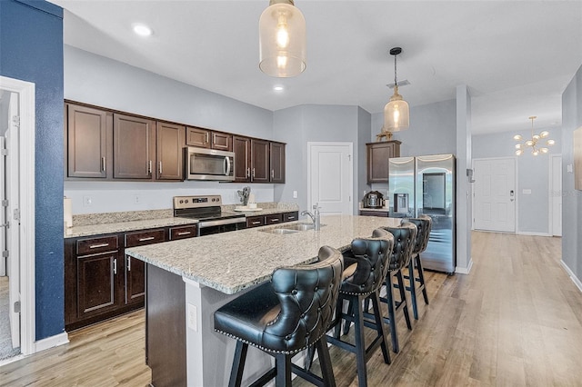 3519 Fernanda Dr, Deltona, FL 32738 - kitchen featuring appliances with stainless steel finishes, a sink, dark brown cabinetry, light wood-style flooring, and a breakfast bar