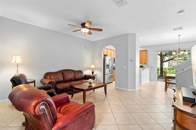 living room featuring ceiling fan, light tile patterned floors, arched walkways, baseboards, and a chandelier