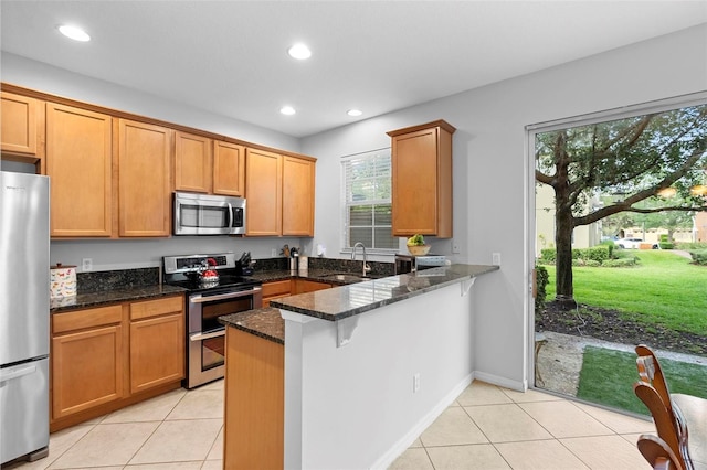 kitchen featuring stainless steel appliances, light tile patterned floors, a sink, a peninsula, and recessed lighting