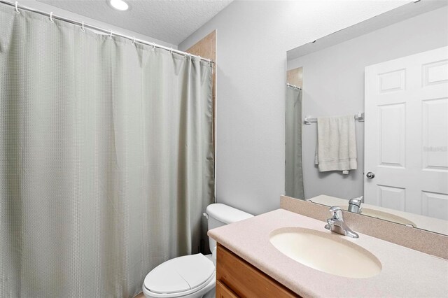 bathroom with toilet, a textured ceiling, and vanity