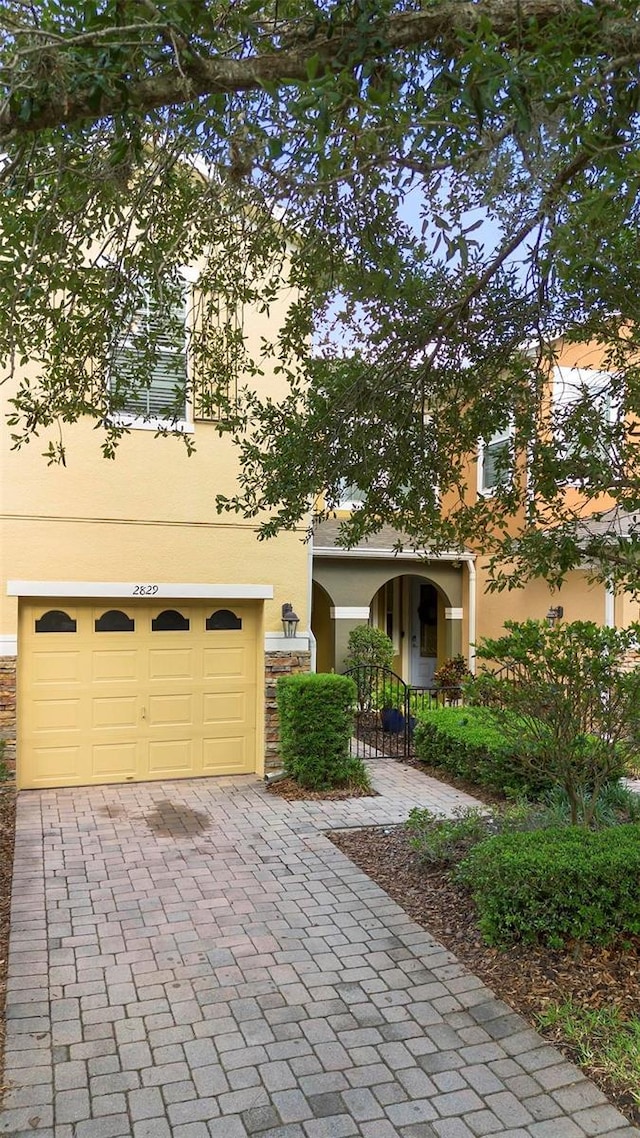2829 Shady Willow Ln, Oviedo, FL 32765 - view of property hidden behind natural elements featuring stucco siding, a garage, stone siding, and decorative driveway