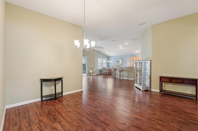 living area featuring a chandelier, vaulted ceiling, wood finished floors, and baseboards