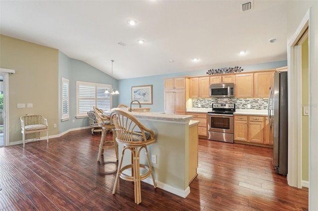 kitchen featuring stainless steel appliances, light brown cabinets, vaulted ceiling, dark wood-style floors, and recessed lighting