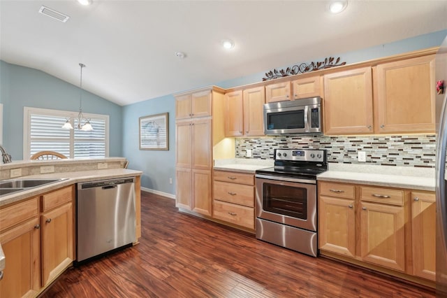 kitchen featuring appliances with stainless steel finishes, light brown cabinets, backsplash, lofted ceiling, and a sink