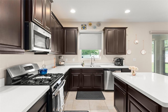 488 Kistler Cir, Clermont, FL 34715 - kitchen with stainless steel appliances, a sink, light countertops, dark brown cabinetry, and light tile patterned floors