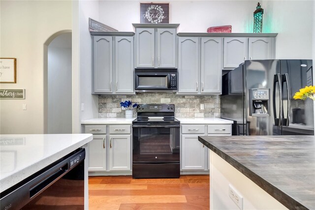 3380 Pawleys Loop N, Saint Cloud, FL 34769 - kitchen with black appliances, arched walkways, decorative backsplash, light wood-style flooring, and light countertops