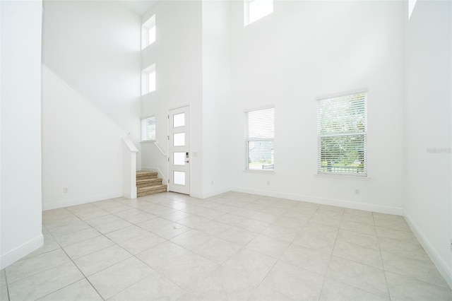6132 Bimini Twist Loop, Orlando, FL 32819 - unfurnished living room with a towering ceiling, stairs, light tile patterned flooring, and baseboards