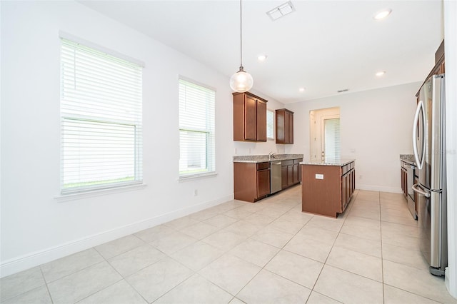 6132 Bimini Twist Loop, Orlando, FL 32819 - kitchen with appliances with stainless steel finishes, a kitchen island, baseboards, hanging light fixtures, and light stone countertops