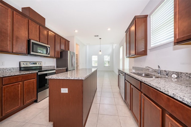 6132 Bimini Twist Loop, Orlando, FL 32819 - kitchen featuring appliances with stainless steel finishes, a kitchen island, light tile patterned flooring, a sink, and light stone countertops