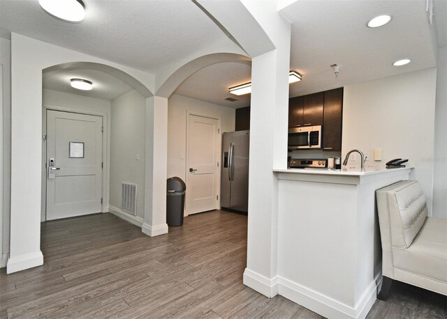 14501 Grove Resort Ave Unit 3741, Winter Garden, FL 34787 - kitchen featuring stainless steel appliances, arched walkways, light countertops, baseboards, and light wood-style floors